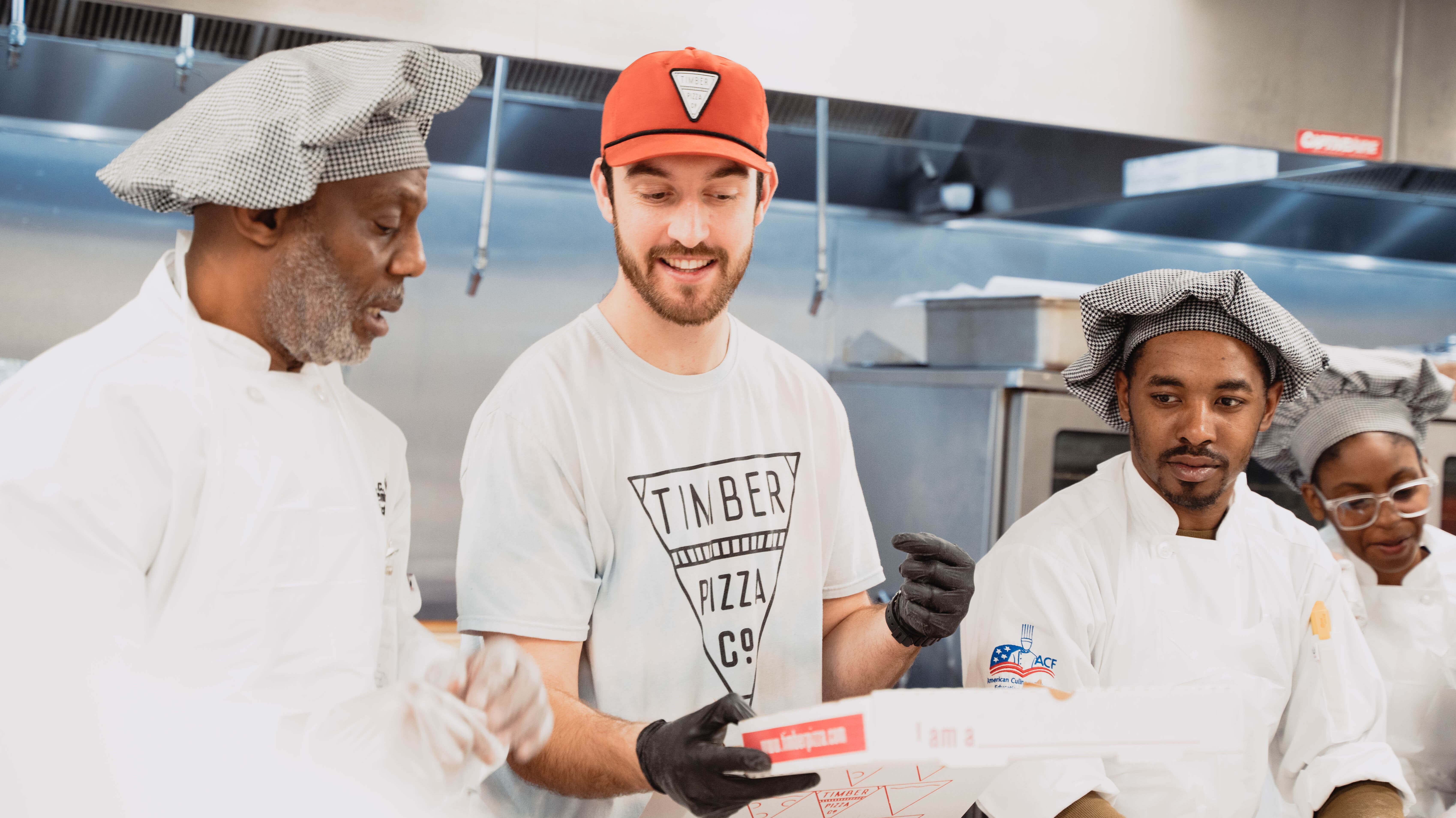 Luke Watson '18 speaking with a head chef and other cooks at the Timber Pizza store in Washington, D.C.