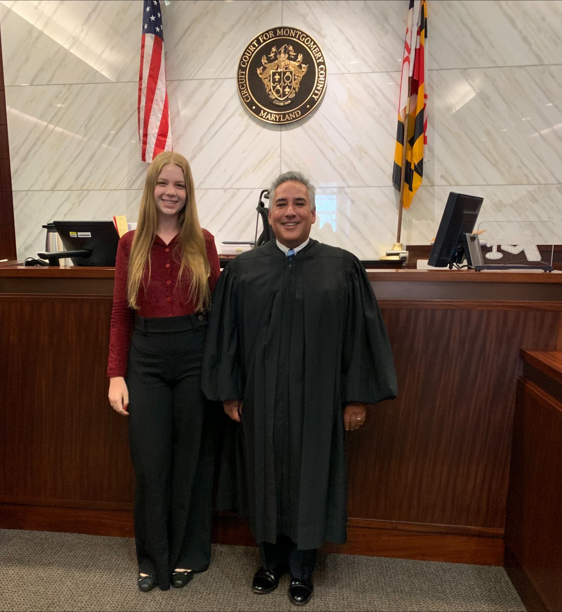 Zen Gordon ’26 and the Hon. Carlos F. Acosta ’85, M.A. ’91 posing for a picture in Acosta's courtroom.