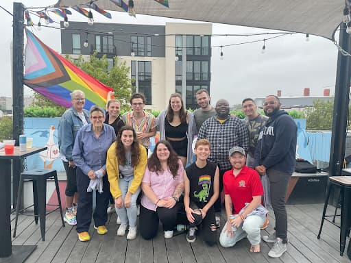 Members of the Pride Mentorship program posing for a picture in front of a Pride Flag