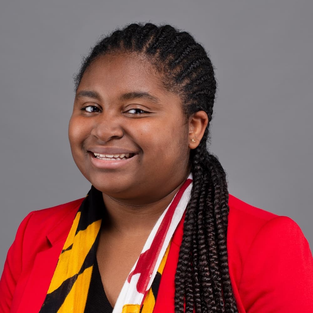 A professional headshot of Jade Kennedy, who has a Maryland-themed scarf around her neck.