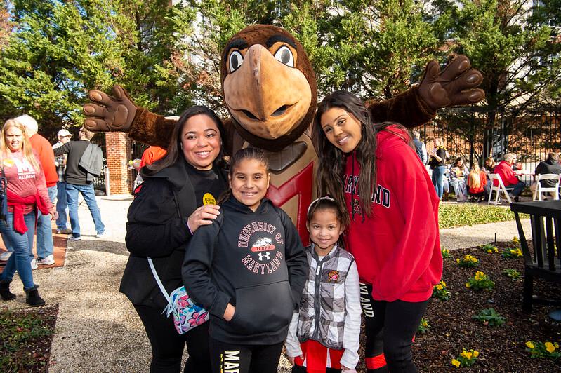 Testudo mascot posing with a family of hour at the Moxley Gardens at the Homecoming Tailgate