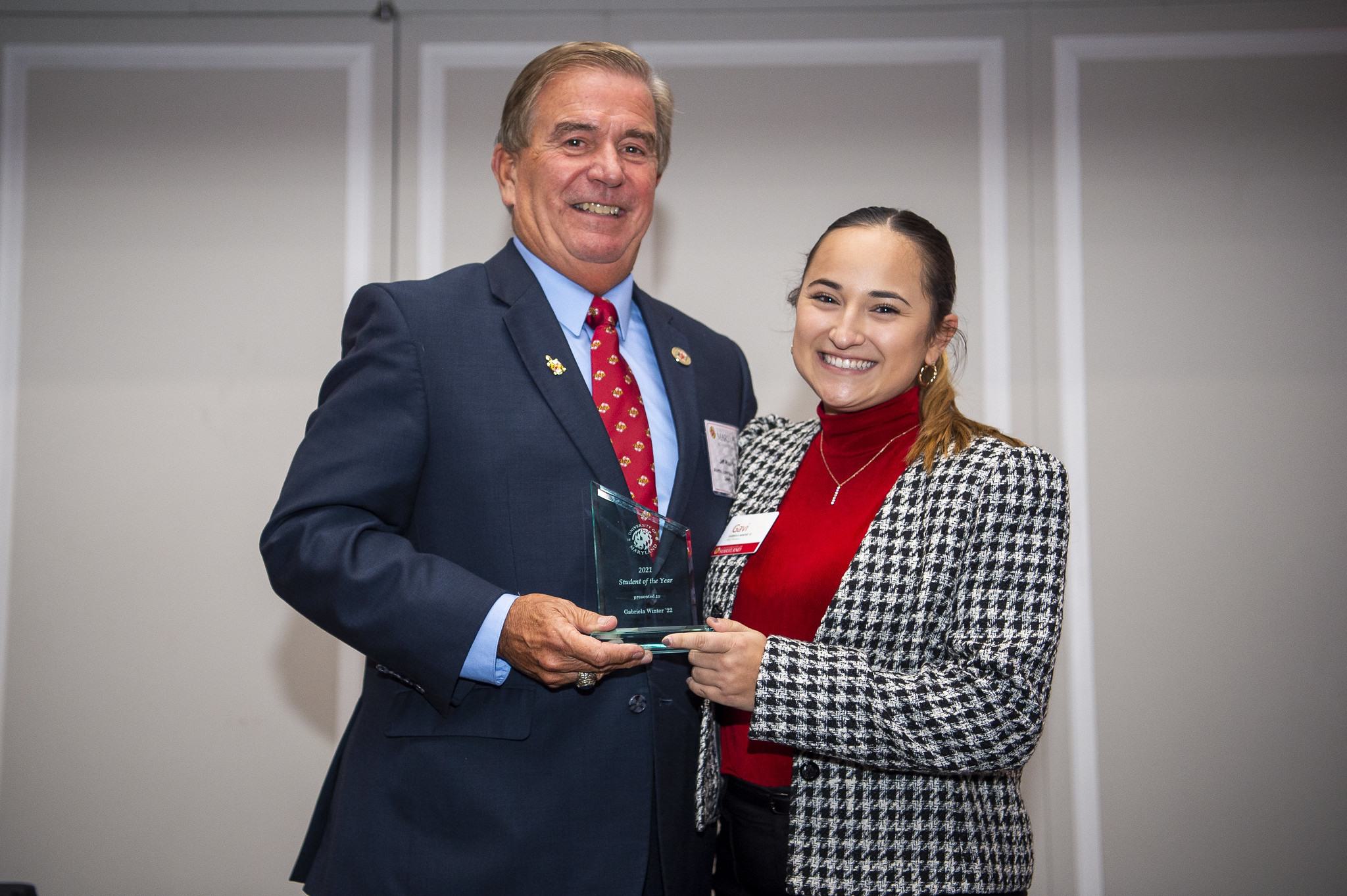 Gabriela "Gabi" poses on stage with Alumni Board President Jeffrey Rivest, after receiving her award for Student Volunteer of the year