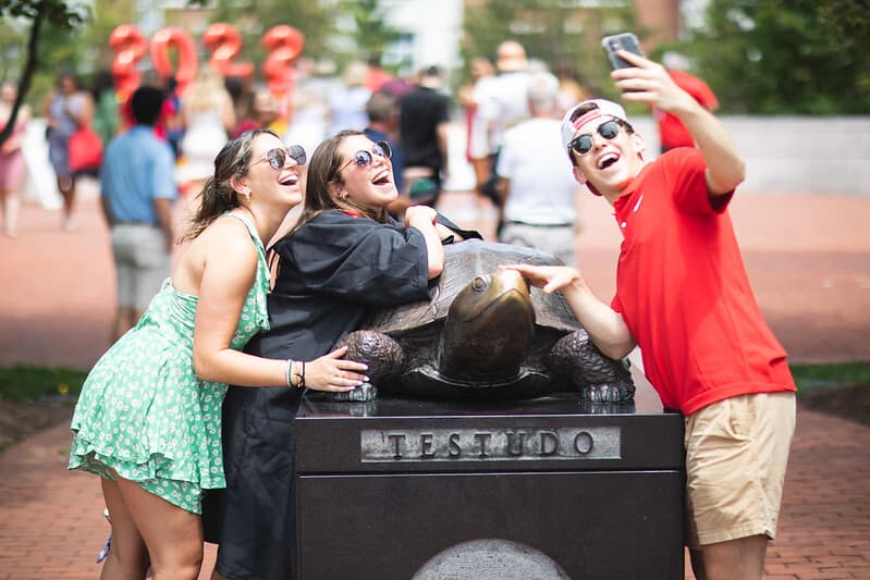 New graduate takes selfie with Testudo statue outside of Riggs Alumni Center