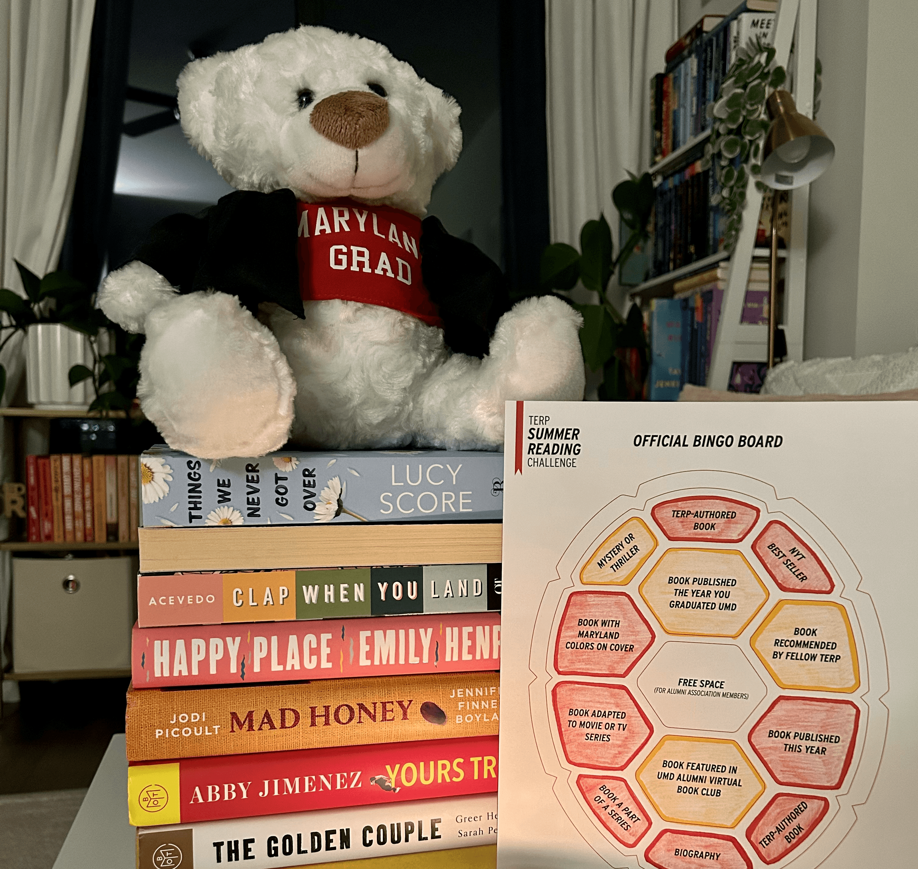 stack of books with summer reading bingo sheet and a stuffed bear with a terps shirt