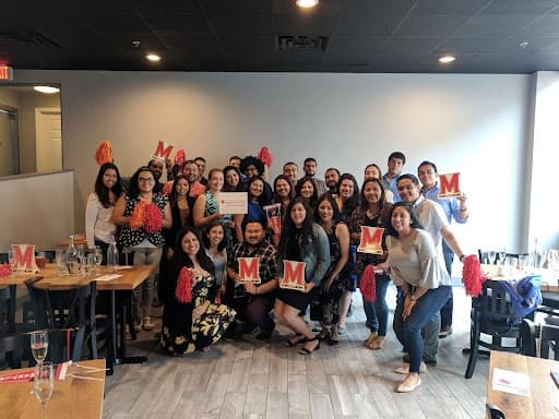 Group of University of Maryland Alumni from the LatinX Alumni Network pose together in the restaurant where they celebrate their award for Network of the Year