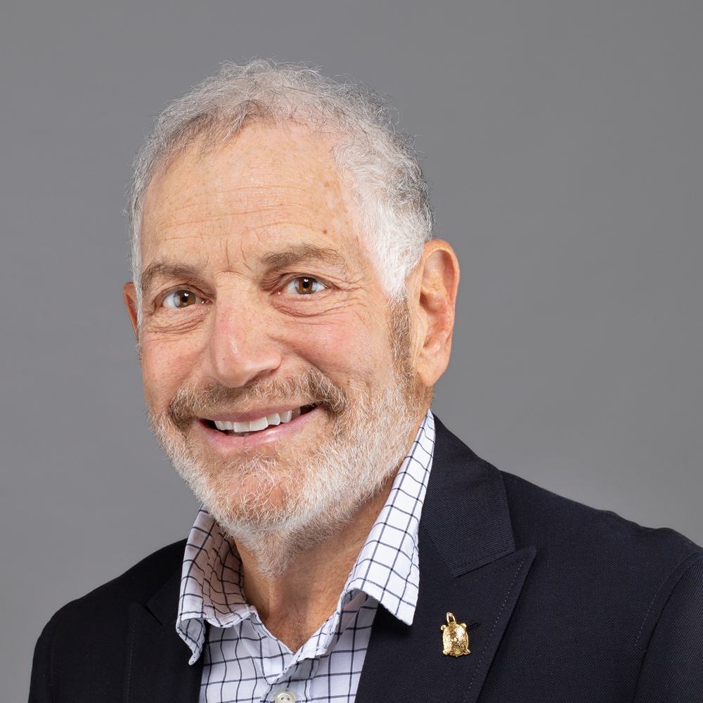 A professional headshot of Jordan Goodman, with a gold Terrapin pin on the right lapel.