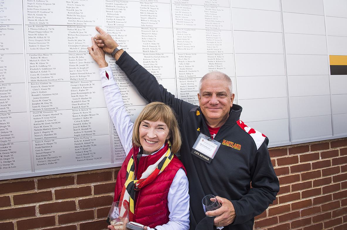 Gretchen Jankovitz '75 and Mark Jankovitz '75 pointing to their names on the Frann G. & Eric S. Francis Lifetime Member Wall