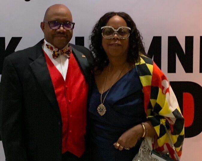Jehnell Adams-Linkins & Jerome Linkins, Sr. wear Maryland colors in front of a UMD event backdrop