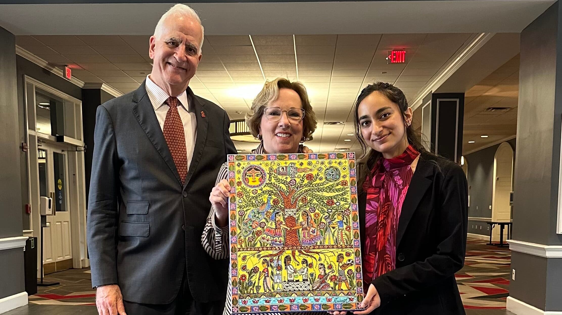 Vainavi presenting a piece of her Madhubani artwork as a token of gratitude to Roger and Karen Winston for their contributions to the Honors College.
