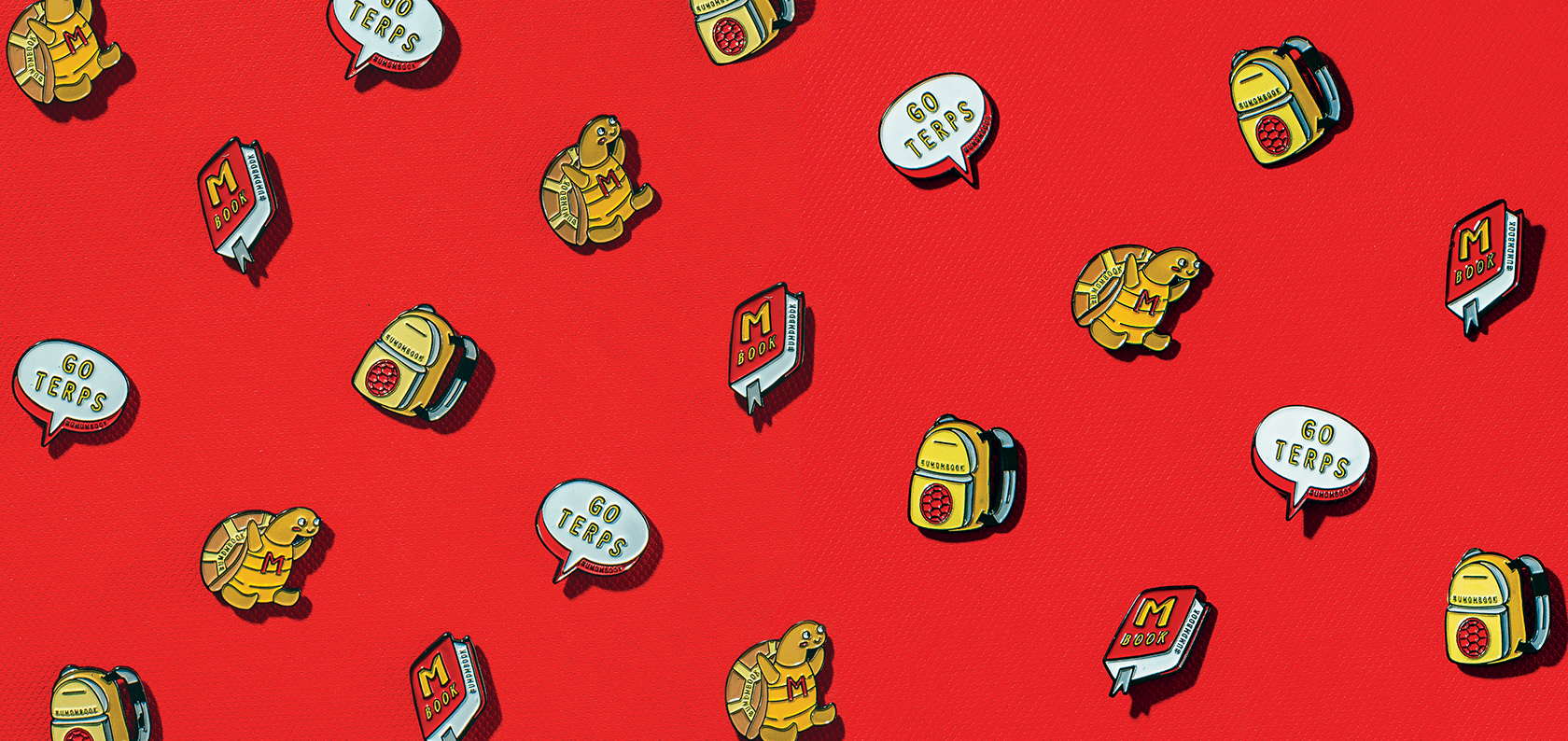 Organized pattern of illustrated enamel pins depicting Testudo, and the M Book on a Maryland Red Background
