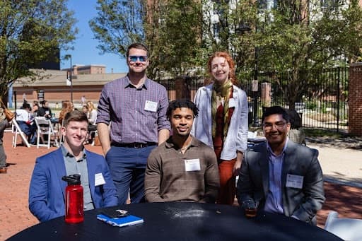 Attendees pose for a photo around a table on the Eleanor F. and Charles Young Jr. Garden Terrace of Samuel Riggs IV Alumni Center during networking hour, presented by AESU, of the 2022 Young Alumni Conference.