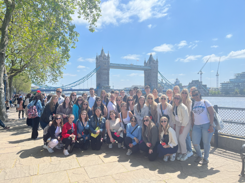 group of young alums in front of the London Bridge