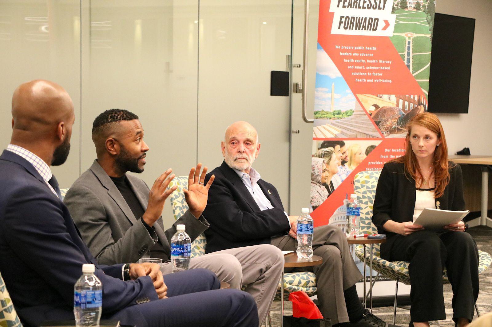 A man speaking as three others listen intently